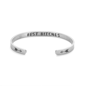 Close-up detail of 'BEST BITCHES' engraving on minimalist stainless steel cuff bracelet