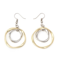 Detail of gold and silver layered irregular circular earrings on a white background