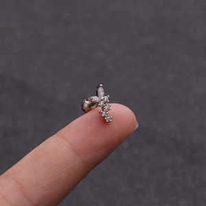 Silver butterfly stud earring with clear cubic zirconia held on a finger for size