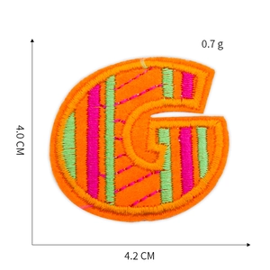 Detailed view of letter G embroidery patch in orange and green stripes with dimensions