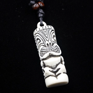 Macro detail of ivory resin Tiki pendant with black engravings and wooden beads