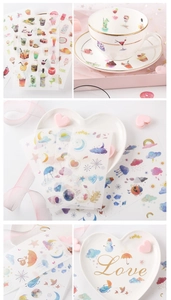 Detailed view of watercolor stickers with cute drink and sky motifs next to ceramic tableware
