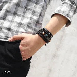 Detail of layered leather bracelet set featuring metal feather charm and turquoise beads