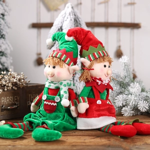 Pair of plush Christmas elf dolls in red and green outfits on a rustic wooden table