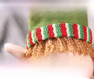 Detailed macro shot of a Christmas elf doll face with striped knit hat and sand filling