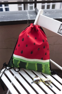 Sac à cordon pastèque sur chaise blanche avec lunettes de soleil sous lumière naturelle