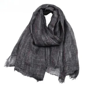 Macro detail of dark grey jacquard scarf showing red plaid pattern and frayed edges