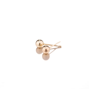 Macro view of polished gold sphere stud earrings with classic post design and mirror finish