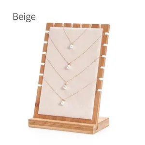 Detail of four golden pearl necklaces displayed on a beige velvet bamboo jewelry stand