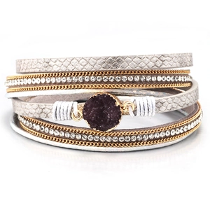 Detail of multi-layer wrap bracelet with silver leather, gold chain and purple crystal