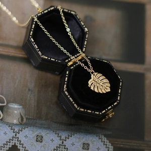 Gold-plated stainless steel monstera leaf necklace displayed in a vintage velvet jewelry box