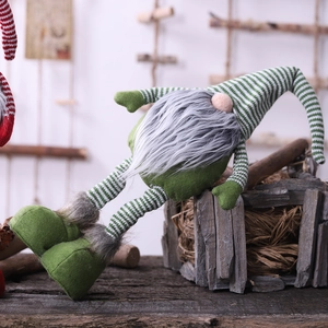 Christmas faceless gnome plush toy with striped long hat and green boots on wooden desk