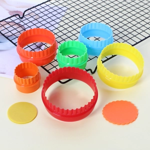 Multi-colored plastic cookie cutters in various sizes with wavy edges for baking