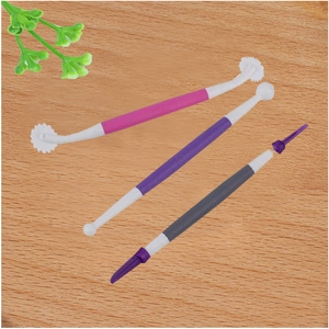 Close-up of pink, purple, and black plastic fondant shaping tools on a wooden background