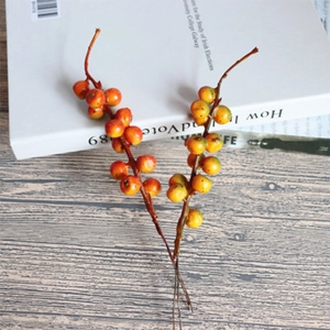 Artificial orange berry stems on wood table with book for rustic home floral decor