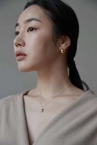 Elegant model wearing a minimalist gold oval necklace and stud earrings jewelry set