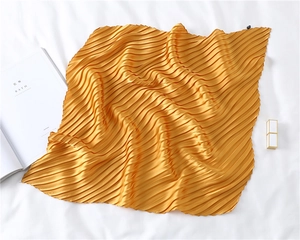 Detail of golden pleated silk-like scarf with fine accordion folds on white background