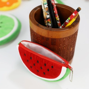Watermelon plush coin purse with red zipper and bead chain on a wooden desk setup
