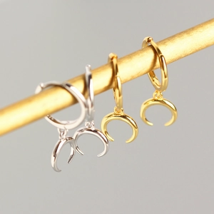 Detail view of gold and silver S925 sterling silver crescent moon hoop earrings on metal rod
