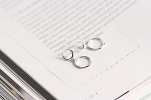 Macro view of S925 sterling silver hoop earrings with crescent moon pendants on book