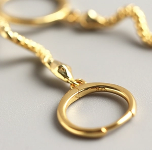 Macro view of gold snake drop earring showing the 925 silver hallmark on the clasp