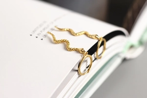 Macro view of gold S925 sterling silver long snake-shaped earring on book pages