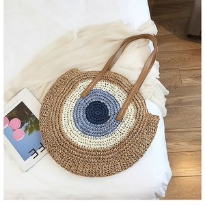 Détail d'un sac de plage rond en paille avec motifs circulaires et anses en cuir