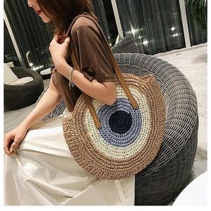 Détail du sac de plage rond en paille tressée multicolore avec bandoulière en cuir marron