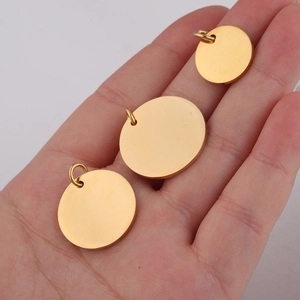 Close-up of three different sized polished golden steel round pendants held in a hand