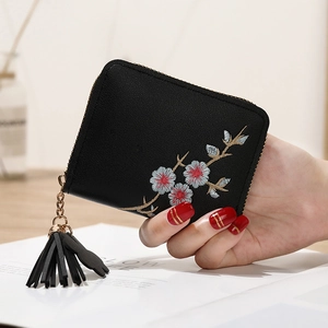 Détail du petit porte-monnaie en cuir PU noir avec broderies fleurs et pompon élégant