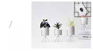 Minimalist faux succulent plants in white pots with sleek metal tripod stands for decor