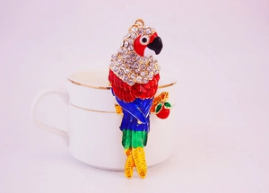 Macro detail of a colorful crystal parrot keychain perched on a branch with gold finish