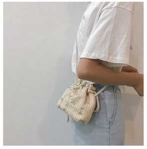 Detailed side view of a beige woven bucket bag with floral embroidery and rope strap