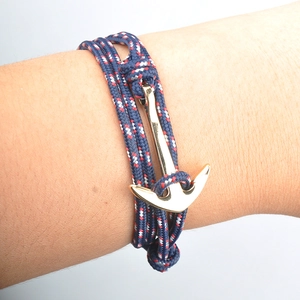 Gros plan d'un bracelet tressé bleu rouge blanc avec fermoir en forme d'ancre dorée