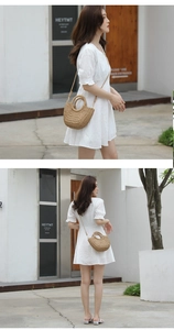 Detail of a woven crescent straw bag featuring a ring handle and slim shoulder strap