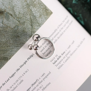 Macro shot of silver metal ring with three spheres on artistic book background