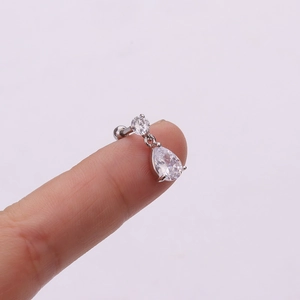 Detailed close-up of a silver flower drop earring with clear zircon crystals on a finger