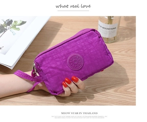 Dettaglio della pochette in nylon viola con logo sportivo e tre scomparti a zip
