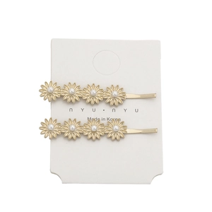 Gold metal daisy hair clips with white pearls on a white paper card background