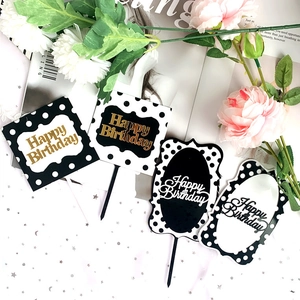 Detail of assorted Happy Birthday cake toppers in black, white and gold acrylic finishes