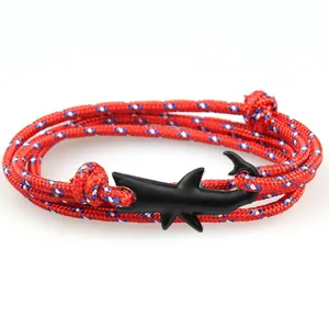 Close-up of a woven red white blue shark bracelet with a matte black shark tail clasp