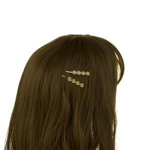 Close-up of golden flower hair clips with crystals on a woman's brown hair