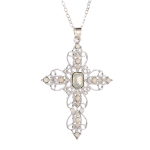 Macro view of silver cross pendant with white gemstones and intricate retro detailing