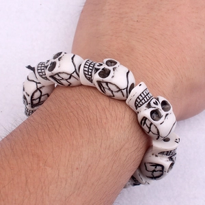 Detailed view of punk skull bracelet with white faux bone beads on an adult wrist