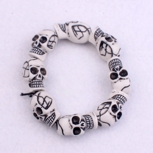 Close-up of white punk skull beads on an elastic bracelet with detailed black carvings