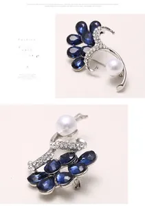 Detailed view of silver alloy brooch with deep blue gemstones and a white pearl accent