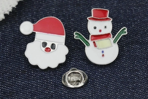 Macro view of cartoon Santa Claus and snowman enamel pins on blue denim fabric