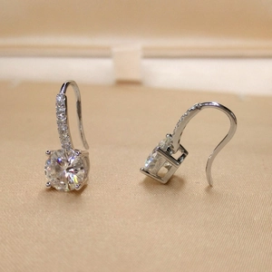Macro detail of silver-tone hoop earrings with round-cut zircons on gold silk