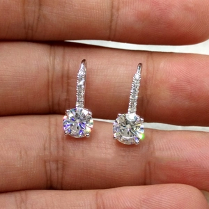 Detail of silver drop earrings with round-cut sparkling cubic zirconia on hand