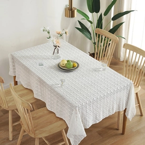 Detailed close-up of white crochet lace tablecloth with geometric patterns on a wood table